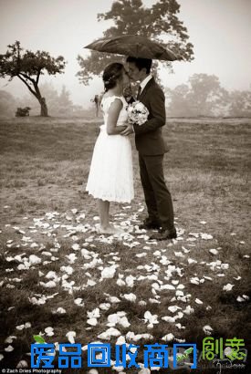 photo4:A husband and wife brave the elements together as they hold hands in their dress and tuxedo, standing among rose petals and protected from the rain under a black umbrella. 这对情侣将所有元素结合在一起,身穿礼服的新人在黑色的雨伞的庇护下紧握双手拥吻在一起,周围散落着玫瑰花瓣。