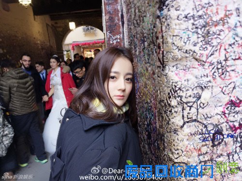 迪丽热巴国外街头拍照 长发披肩头倚城墙美如画