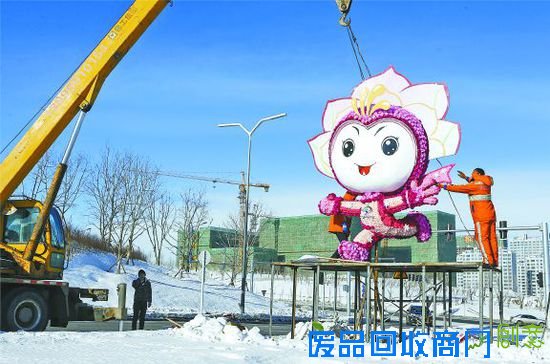 12月24日，在乌鲁木齐市卫星路南延与新医路西延交会路口，工人在安装十三冬吉祥物“雪莲娃”卡通造型。