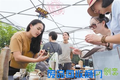 在乐天陶社每周六的创意市集上,景德镇“九烧”工作室的雷鸣(左一)向顾客介绍作品(6月6日摄)。乐天陶社2008年启动创意市集,筛选年轻艺术家展示自己的作品,成为推动当地创意力量萌发的平台。