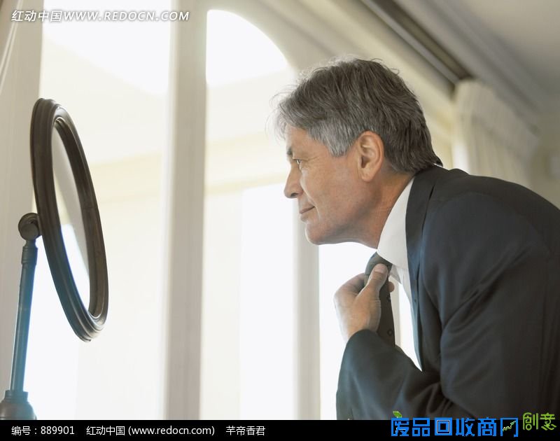 对着镜子整理领结穿西服的外国老年男人侧脸图片 