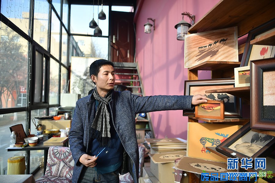 在宁夏银川西夏沙画工作室,刘飞在展示新的流沙工艺沙画(1月4日摄)。