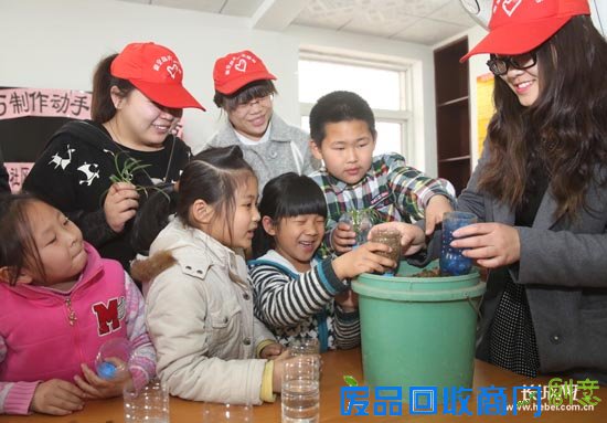 志愿者帮助小朋友在废旧的饮料瓶中装入泥土。通讯员 供图