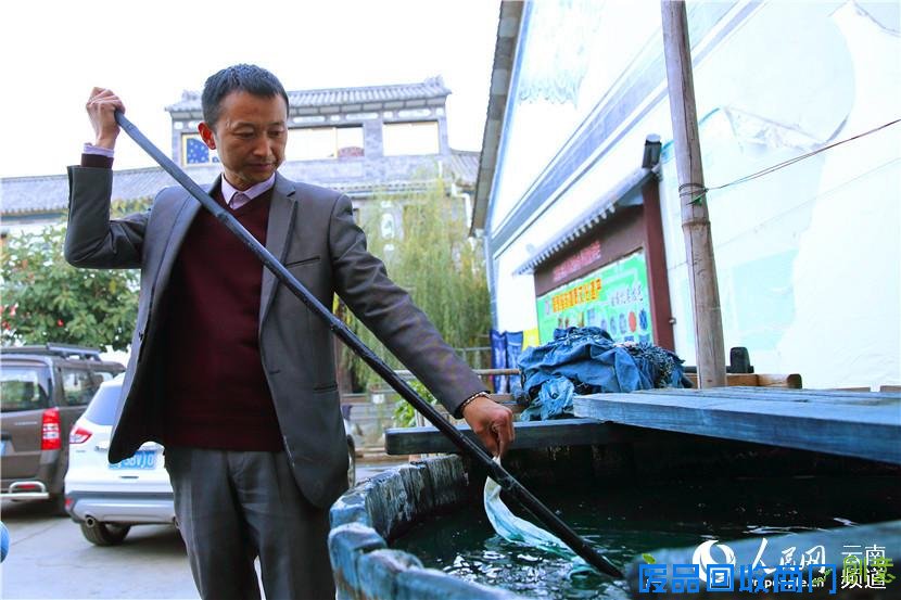 白族扎染技艺传承人段树坤向记者展示染缸内的染布 人民网 薛丹 摄