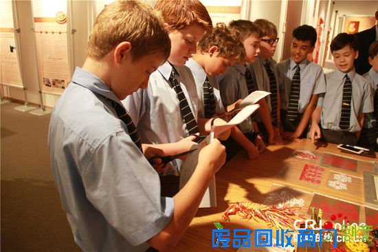 学生们聚精会神地跟艺术家学习剪纸。