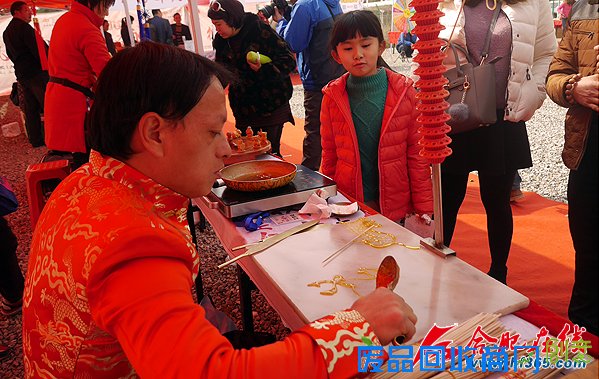 一位小女孩正在观看非遗项目糖画的表演