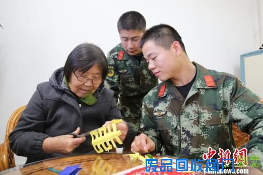 老艺人手把手的教官兵剪纸。