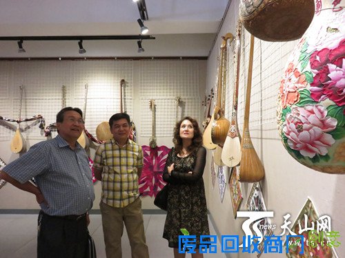 参观者在欣赏器乐展示和葫芦雕刻作品