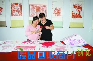 刘金莲左向剪纸爱好者传授剪纸技艺。田国威